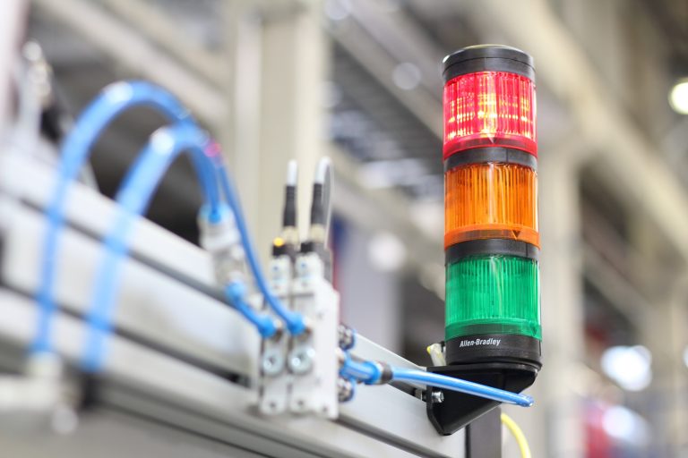 Signallampa med rött, orange och grönt ljus på en maskin i en industrimiljö